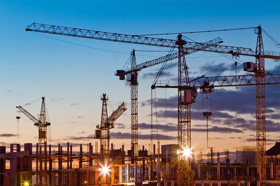 Turmdrehkrane auf einer Großbaustelle in der Abenddämmerung